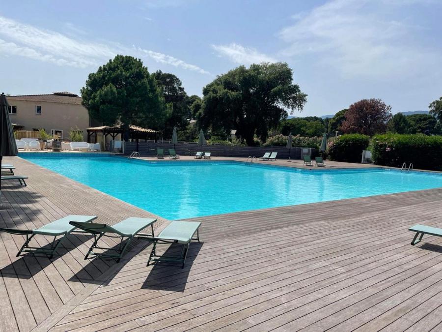 une grande piscine avec deux chaises et une terrasse dans l'établissement Tamaricciu di cala rossa, à Lecci