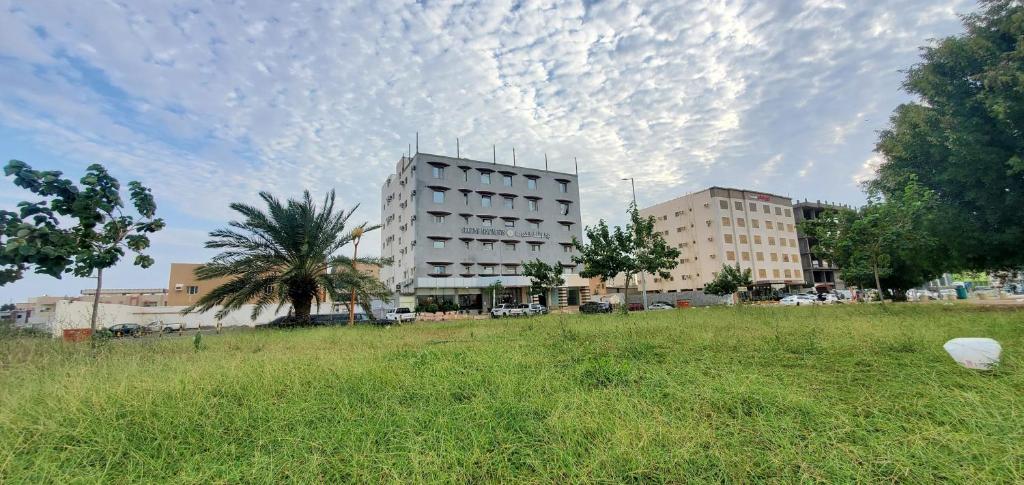 a building in a field of grass with a cloudy sky at Seasons Apartments in Jazan