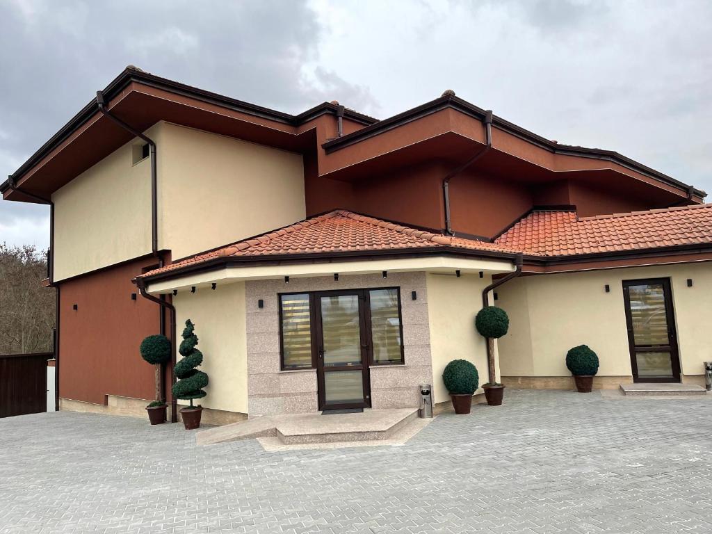 a house with two potted plants in front of it at Хотел Балач in Godech