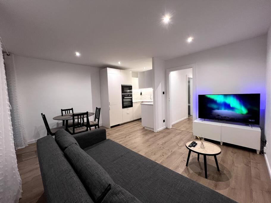 un salon avec un canapé, une télévision et une table dans l'établissement Logement-Proche Strasbourg-rez de jardin-Centre, à Strasbourg