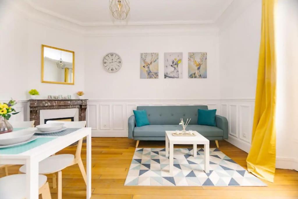 ein Wohnzimmer mit einem blauen Sofa und einem Tisch in der Unterkunft Cocon proche Disneyland Paris (15 mn) in Thorigny-sur-Marne
