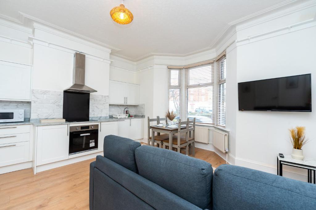 a living room with a blue couch and a kitchen at Coastal One Bedroom Apartment Free Parking in Great Yarmouth