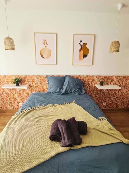 - un lit avec une couverture et 2 photos sur le mur dans l'établissement Charmante maisonnette - St naz- Comme à la maison, à Saint-Nazaire