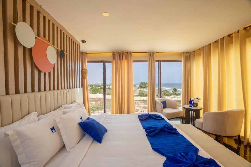 a bedroom with a large bed with a view of the ocean at Marlin All Inclusive Resort in Kasoa