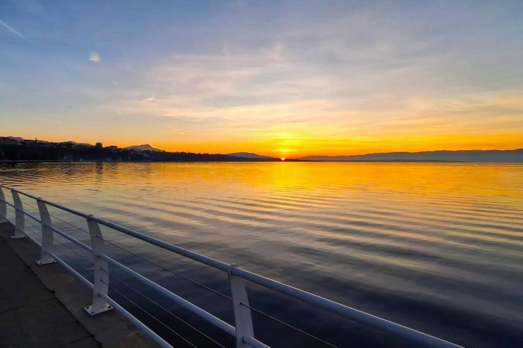 a sunset over a body of water with a pier at Appartement avec vue 180 sur le Lac Léman in Thonon-les-Bains