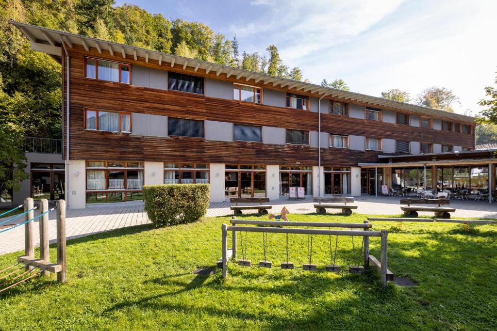 ein Gebäude mit Bänken im Gras davor in der Unterkunft JUFA Hotel Montafon in Bartholomäberg