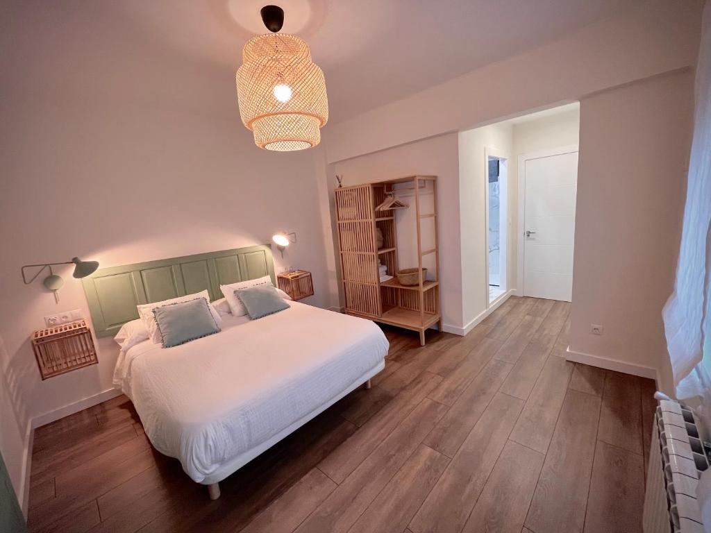 Un dormitorio con una gran cama blanca y una lámpara de araña. en Cámara25 VUT-4088-AS en Avilés