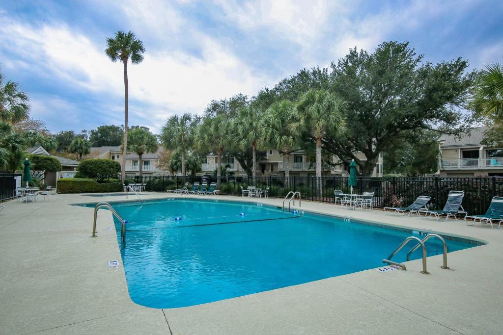 uma grande piscina azul com cadeiras e palmeiras em Happy Place em Isle of Palms