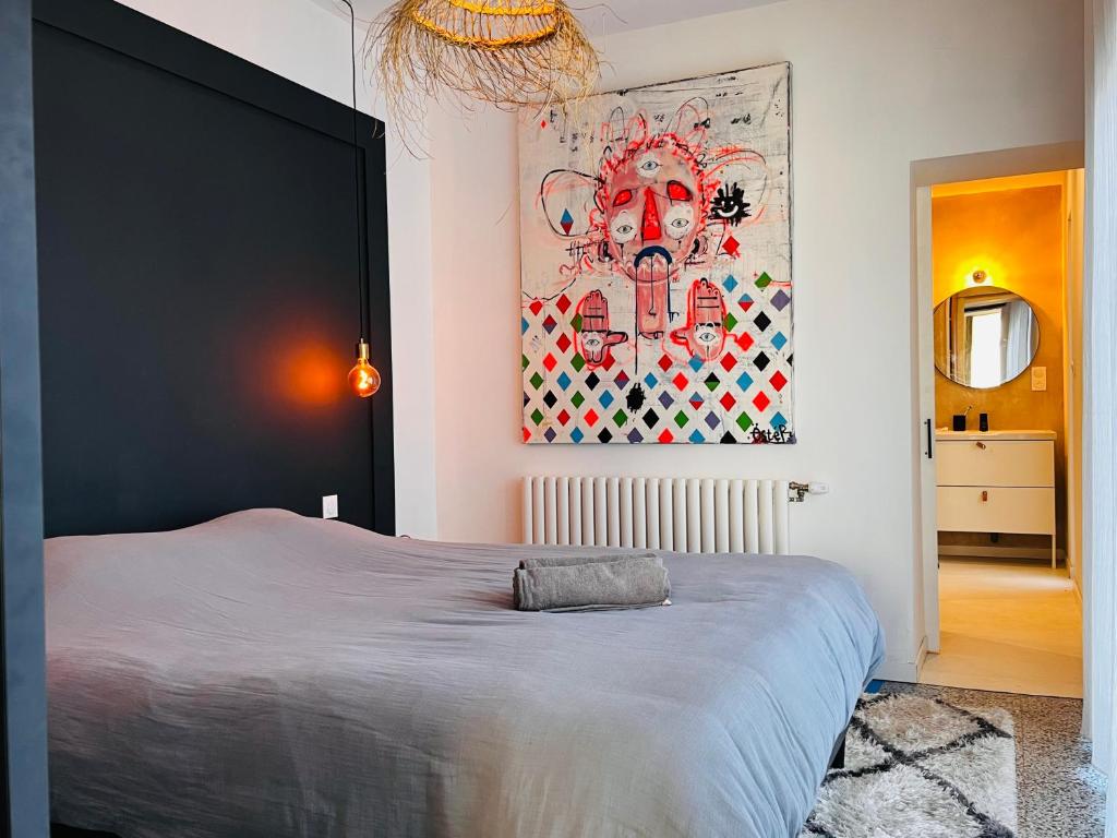1 dormitorio con 1 cama grande y una pintura en la pared en La Baraque Calais Blériot 2, en Sangatte