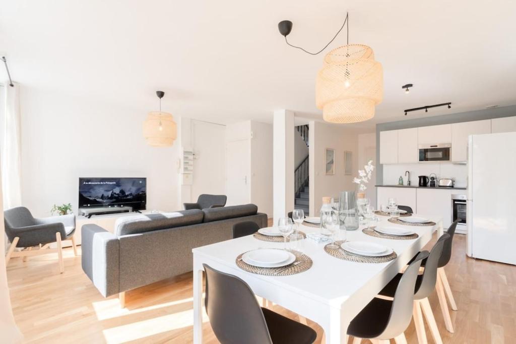 una sala da pranzo e un soggiorno con tavolo e sedie bianchi di Apartment in a new residence with parking a Mouvaux