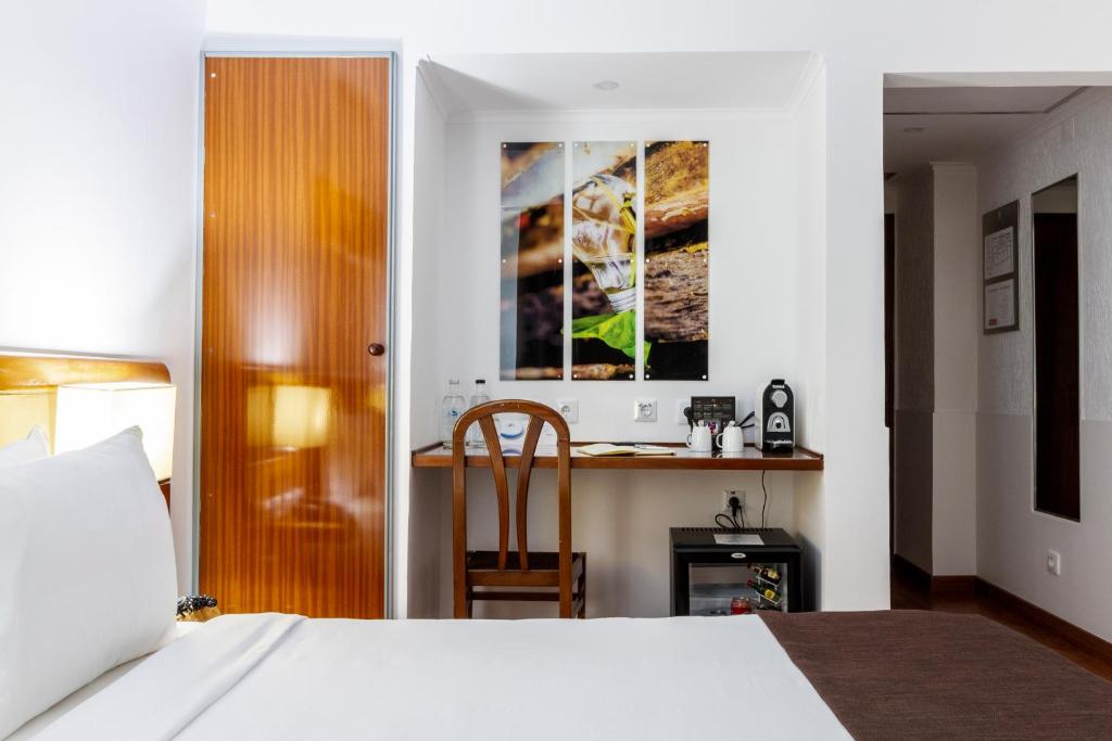 A guest room with a single visible bed and a built-in desk beside a drinks station.