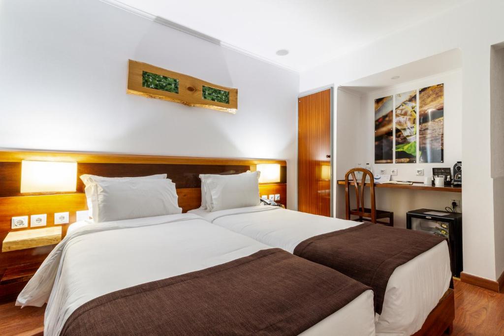 A twin room with padded white bedding, warm wood details and a compact desk area.