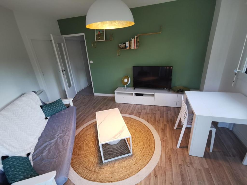 een woonkamer met een bank en een tafel bij Résidence ORION- Appartement pour 2 à 3 personnes- Wifi gratuit in Seignosse
