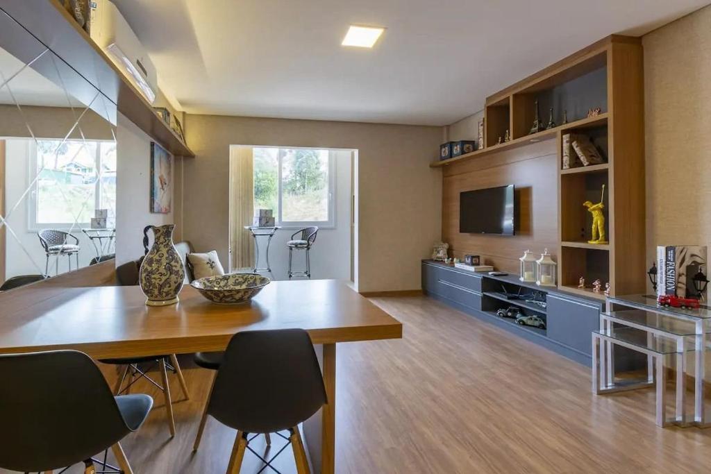 uma sala de estar com uma mesa de jantar e uma televisão em Apartamento Novo e Moderno em Gramado em Gramado