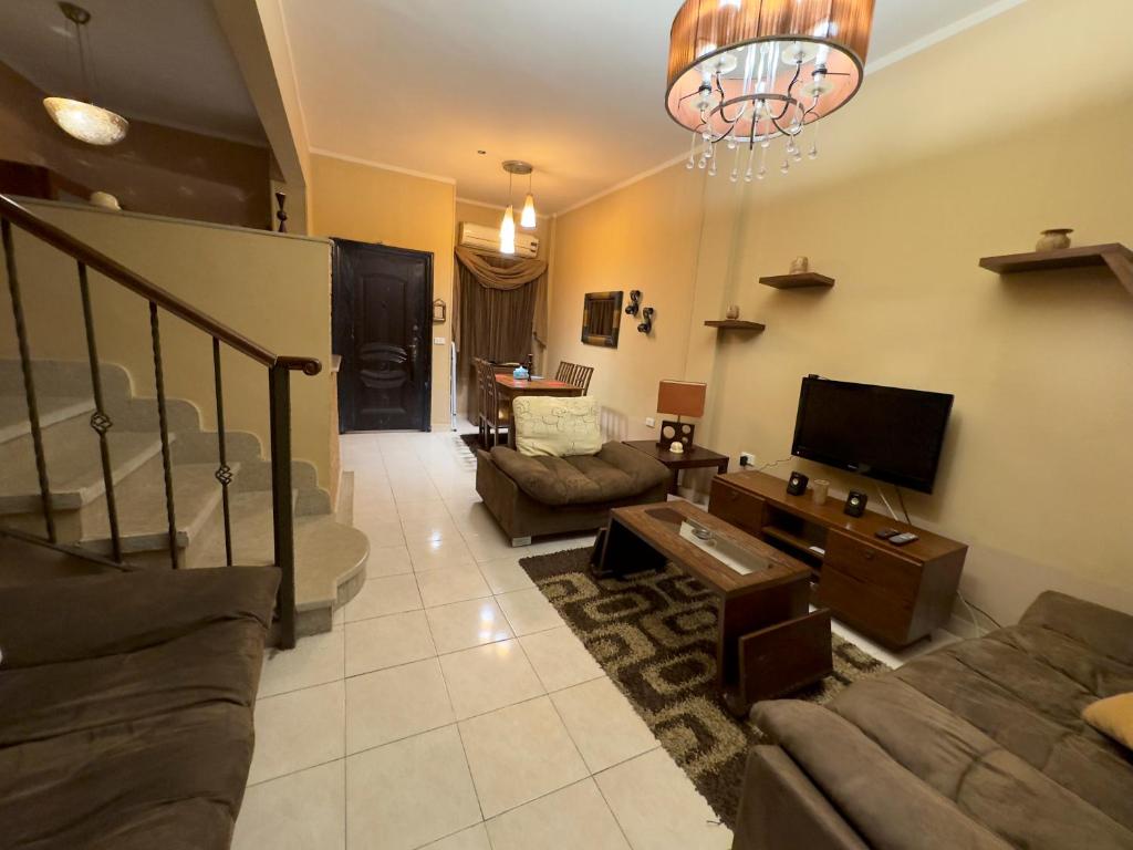 uma sala de estar com um sofá e uma televisão em Cozy Townhouse, with back yard (98) em Sheikh Zayed