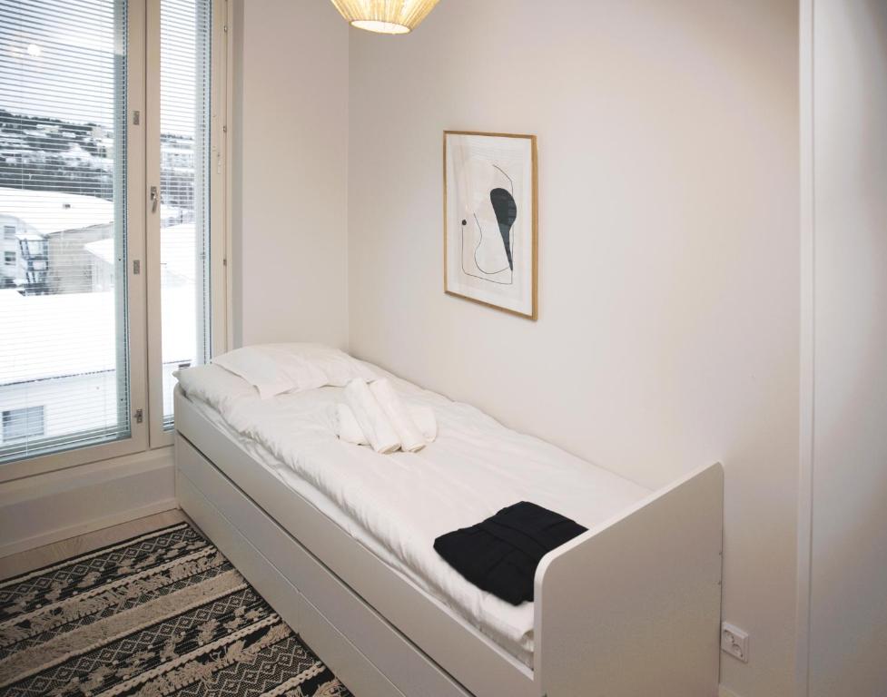a white bed in a room with a window at New 3-Bed Apartment & Free Garage parking & PS5 in Vantaa