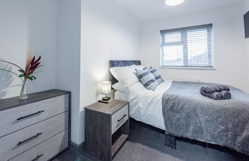 a bedroom with a bed and a dresser and a window at High End Double Room with Own Bathroom Facilities in Bedford