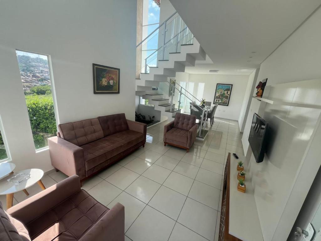 a living room with two couches and a staircase at Condomínio Villa Verde Triunfo in Triunfo