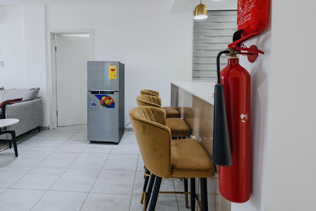 a kitchen with a red fire hydrant and some chairs at The Avery Apartments at Odomaa Place, East Airport in Accra