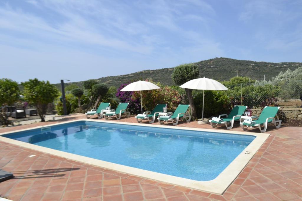 une piscine avec chaises et parasols dans l'établissement Quinta Da Horta, à São Brás de Alportel