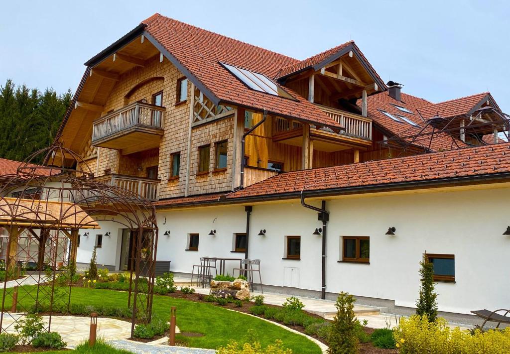 un grand bâtiment en bois avec un toit rouge dans l'établissement Rosenhof Salzburger Seenland, à Straßwalchen