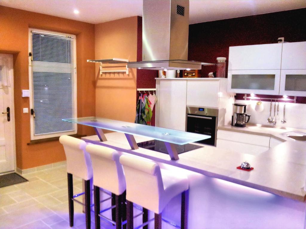 a kitchen with a counter with white cabinets and white chairs at Altes Backhaus in Bad Harzburg