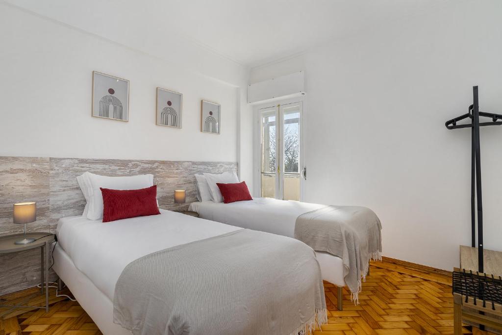 two beds in a white room with red pillows at WHome Peaceful Algés Family Home away from City Noise in Algés