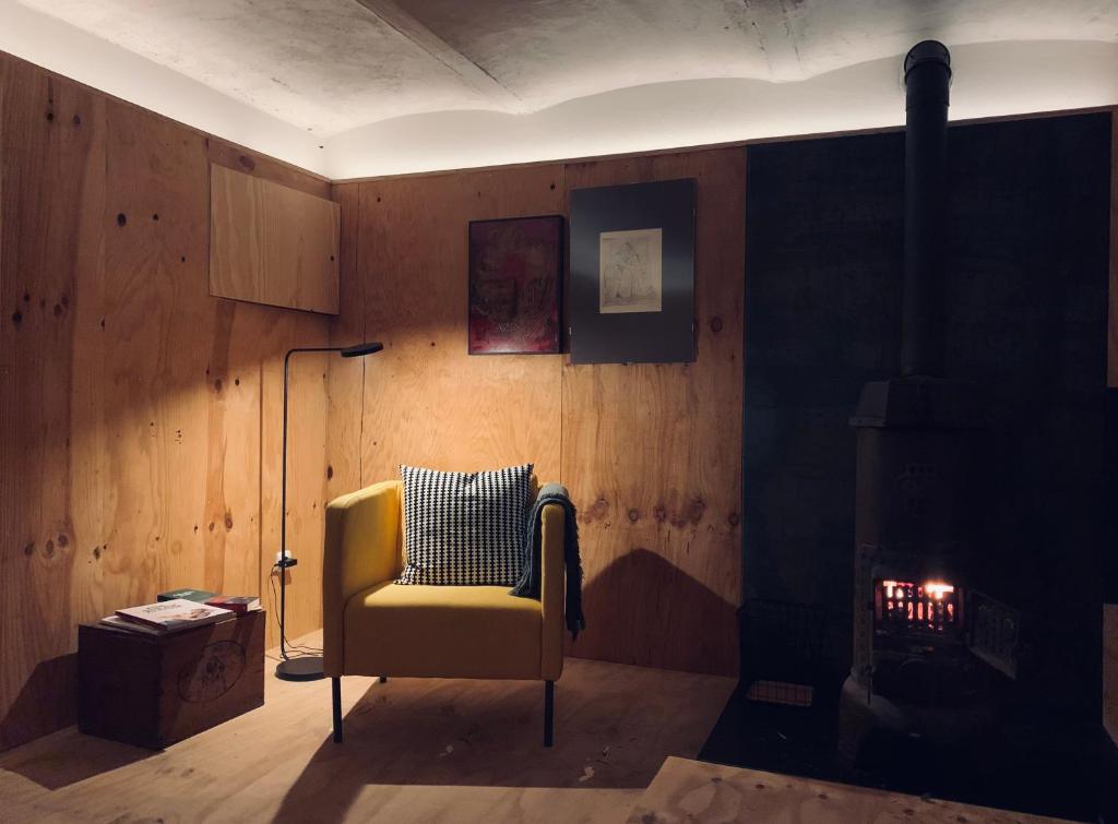 einen gelben Stuhl in einem Zimmer mit Kamin in der Unterkunft Künstlerzimmer in Straden