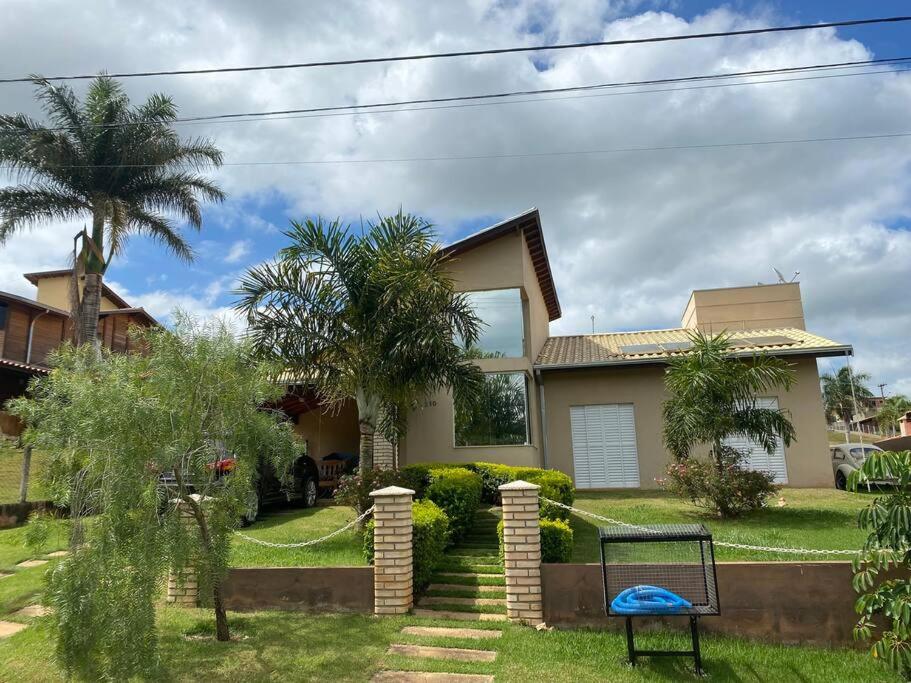 a house with a palm tree in the yard at Casa com piscina no interior em condomínio fechado in Quadra
