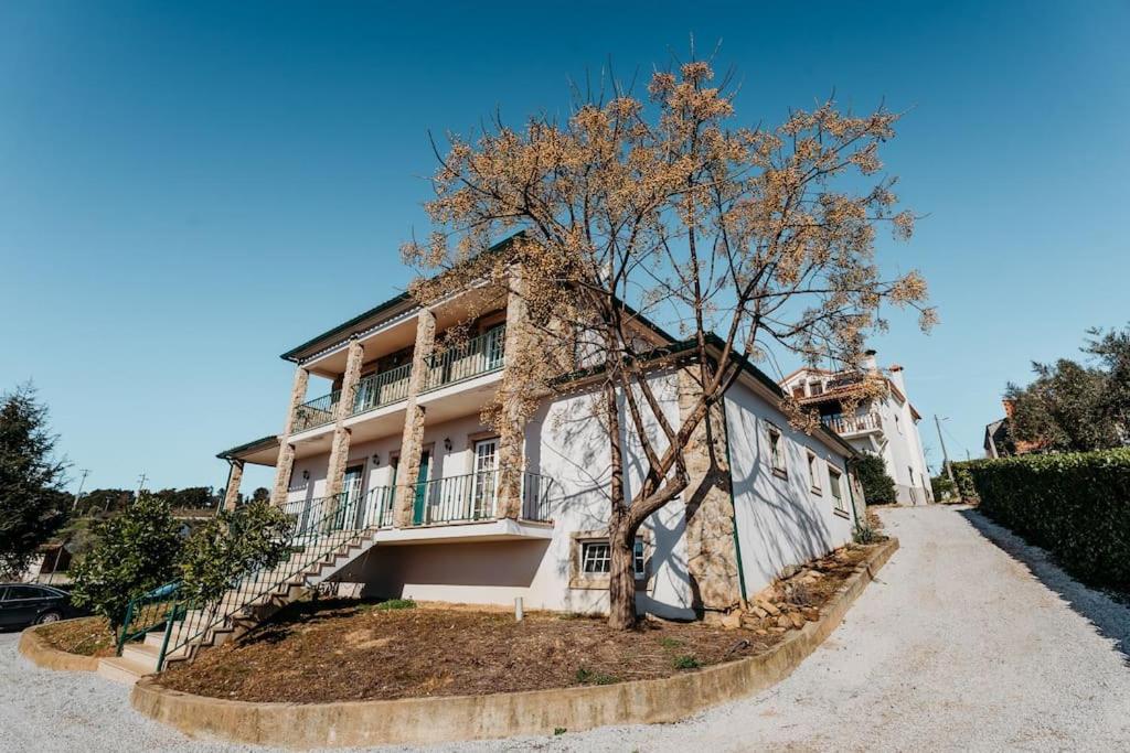 un edificio con un árbol delante de él en A Nossa Casa en Castelejo