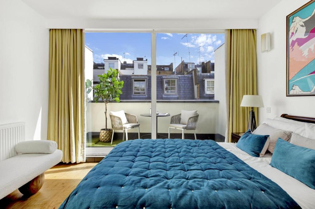 Un dormitorio con una gran cama azul y una gran ventana en 3 bdrm Notting Hill Mews house - 2 balconies en Londres