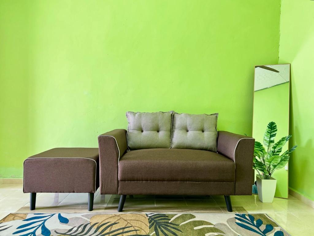 - un canapé dans un salon avec un mur vert dans l'établissement Teratak Tok Ma Rumah Nyatuh, à Kampong Wakaf Tengah