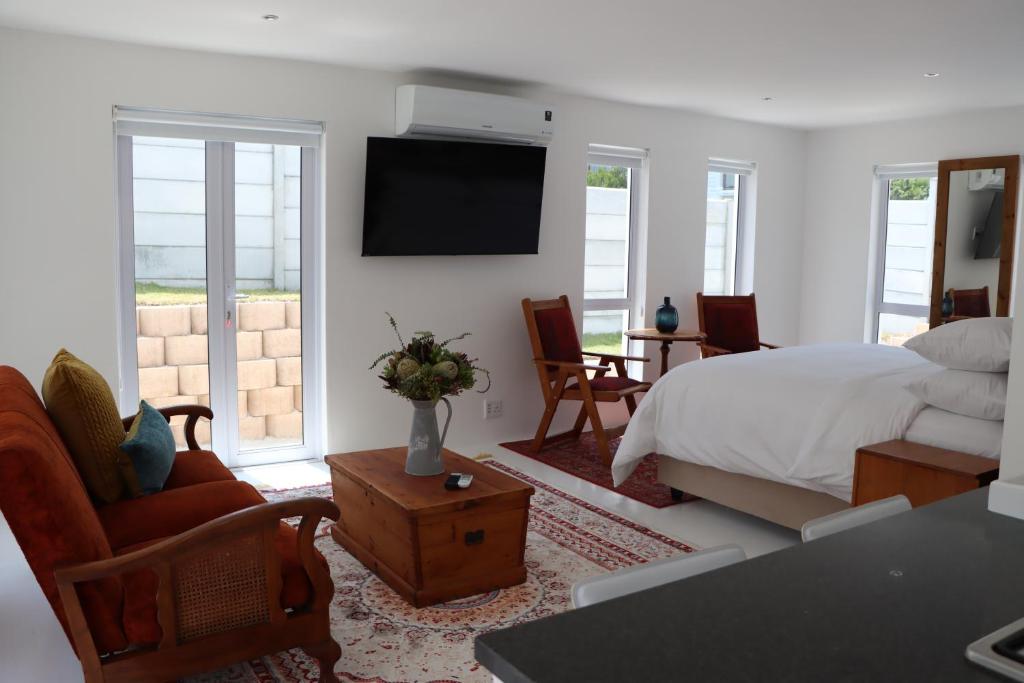 1 dormitorio con 1 cama y TV en la pared en Nivenia Beach House en Bettyʼs Bay