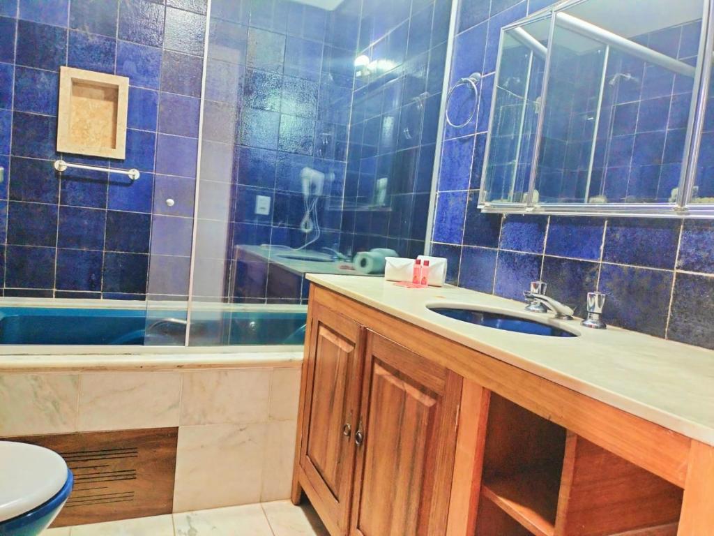 a blue tiled bathroom with a sink and a tub at EcoHotel Vale do Sol in Embu