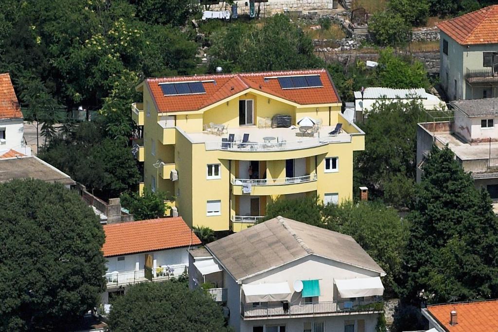 una casa amarilla con paneles solares en el techo en Apartments Vesna, en Gradac