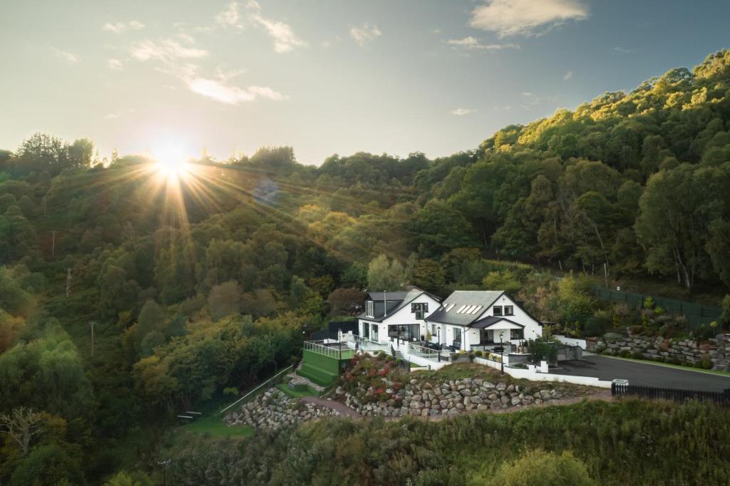 an aerial view of a house in the hills with the sun setting at Fern View House over Loch Ness in Inverness