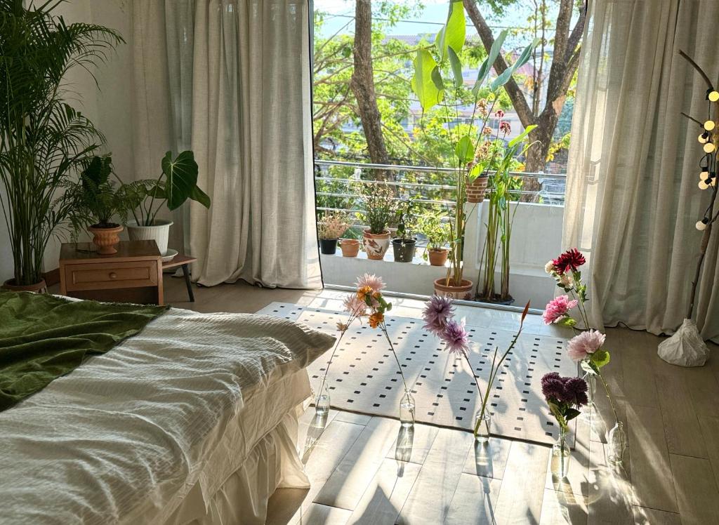 um quarto com uma cama e uma janela com plantas em Sandra’s sweet house em Chiang Mai