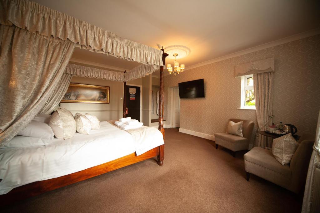 a bedroom with a large bed and a chair at Brackenborough Hotel in Louth
