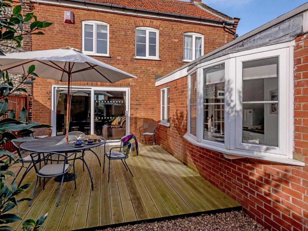 eine Terrasse mit einem Sonnenschirm, einem Tisch und Stühlen in der Unterkunft 3 bed property in Weybourne Norfolk KT069 in Weybourne