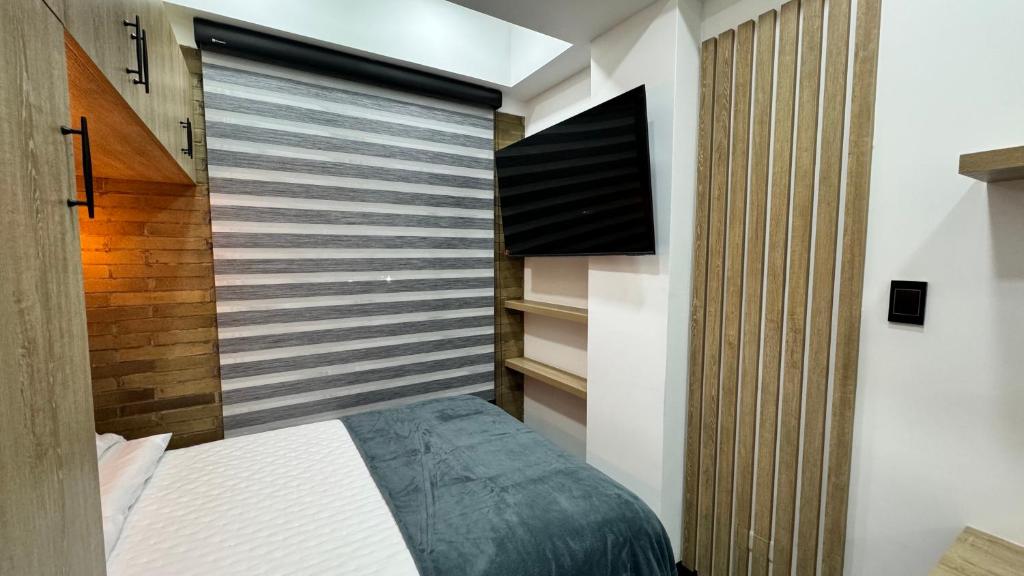 a bedroom with a bed and a flat screen tv at Living para 2 personas, Apartaestudio - Santa Bárbara, Bogotá in Bogotá