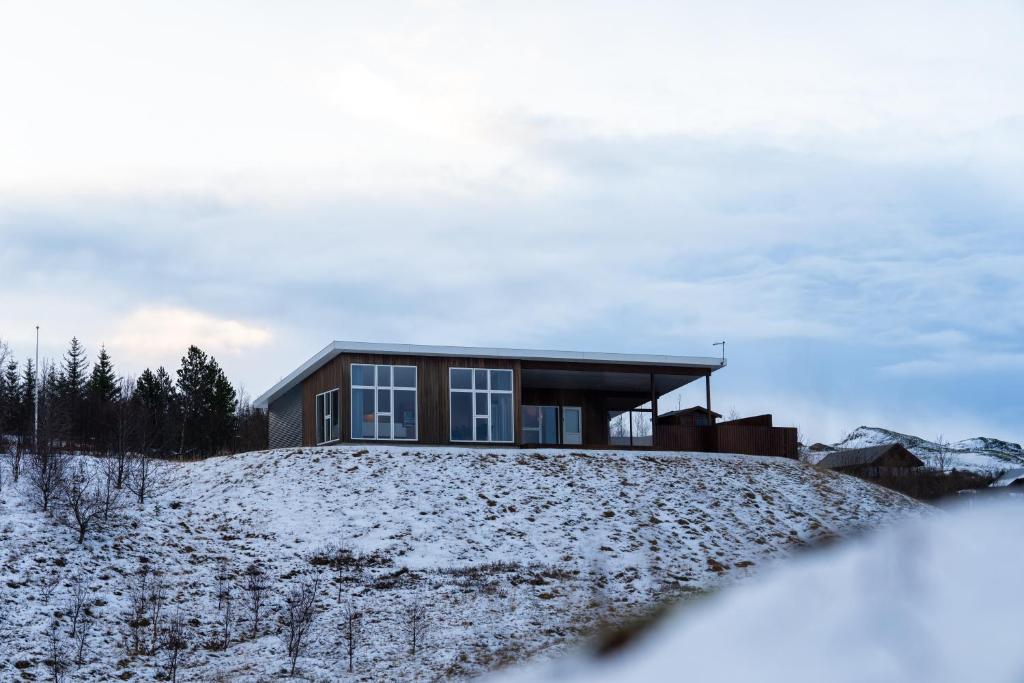 dom na szczycie pokrytego śniegiem wzgórza w obiekcie Golden Circle Villa - Hot Tub & Sauna w mieście Flúðir