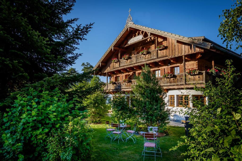 ein großes Holzhaus mit Tischen und Stühlen im Hof in der Unterkunft Landhaus Christl am See in Bad Wiessee