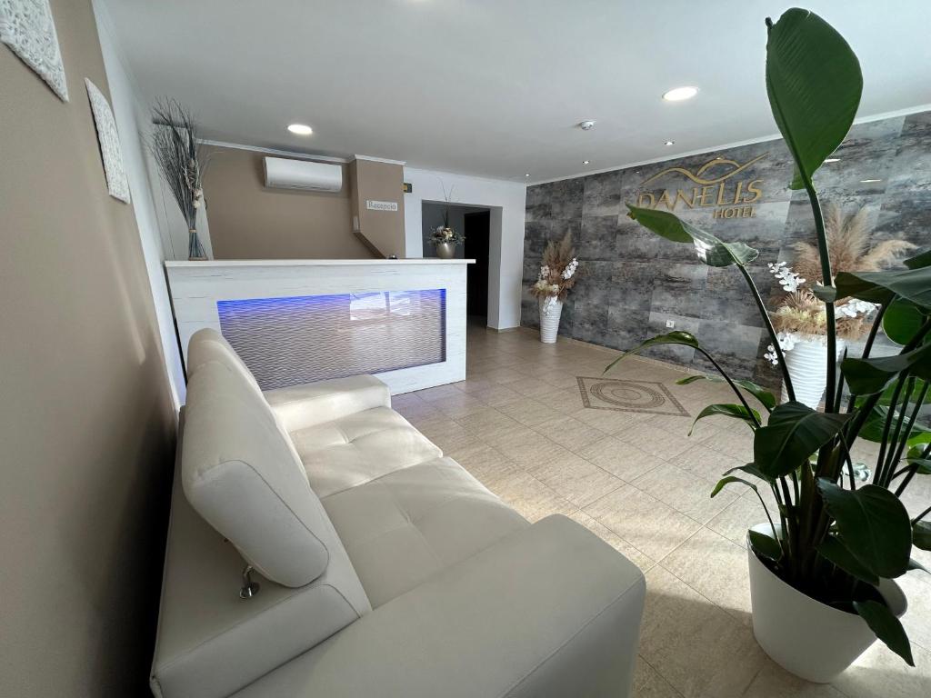 a living room with a white couch and a tv at Danelis Hotel in Edelény