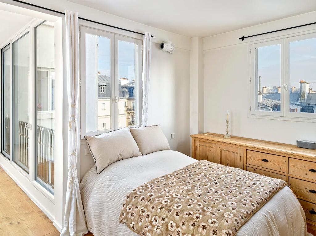 Schlafzimmer mit einem Bett und großen Fenstern in der Unterkunft Saint Sulpice Towers in Paris