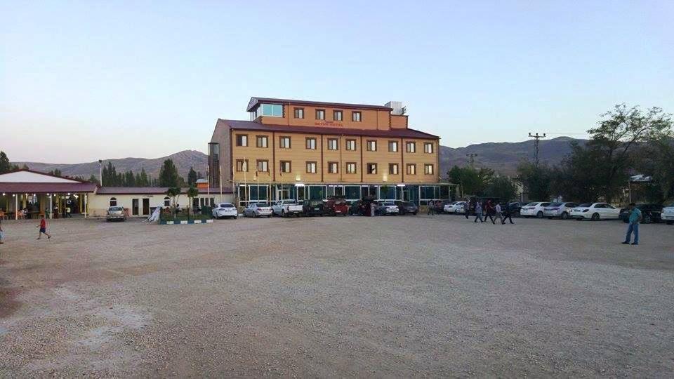 ein großes Gebäude mit Autos auf einem Parkplatz in der Unterkunft Butik Ertur Hotel in Doğubayazıt