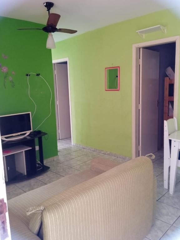ein Wohnzimmer mit einem Sofa und einer grünen Wand in der Unterkunft Apartamento para temporada in Mongaguá