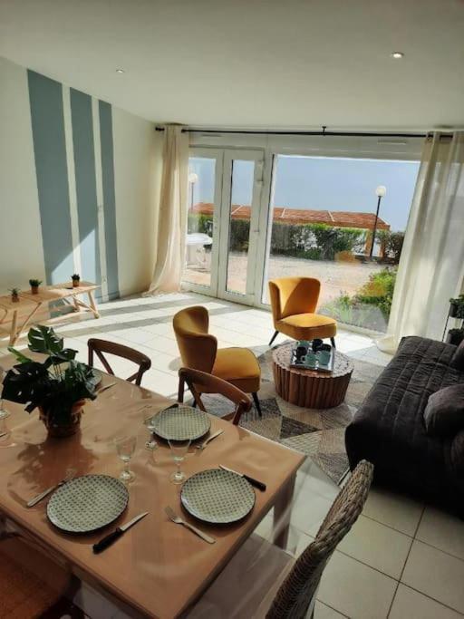 un salon avec une table et des chaises en bois dans l'établissement Appart magnifique avec une vue exceptionnelle OLERON, à La Bernerie-en-Retz