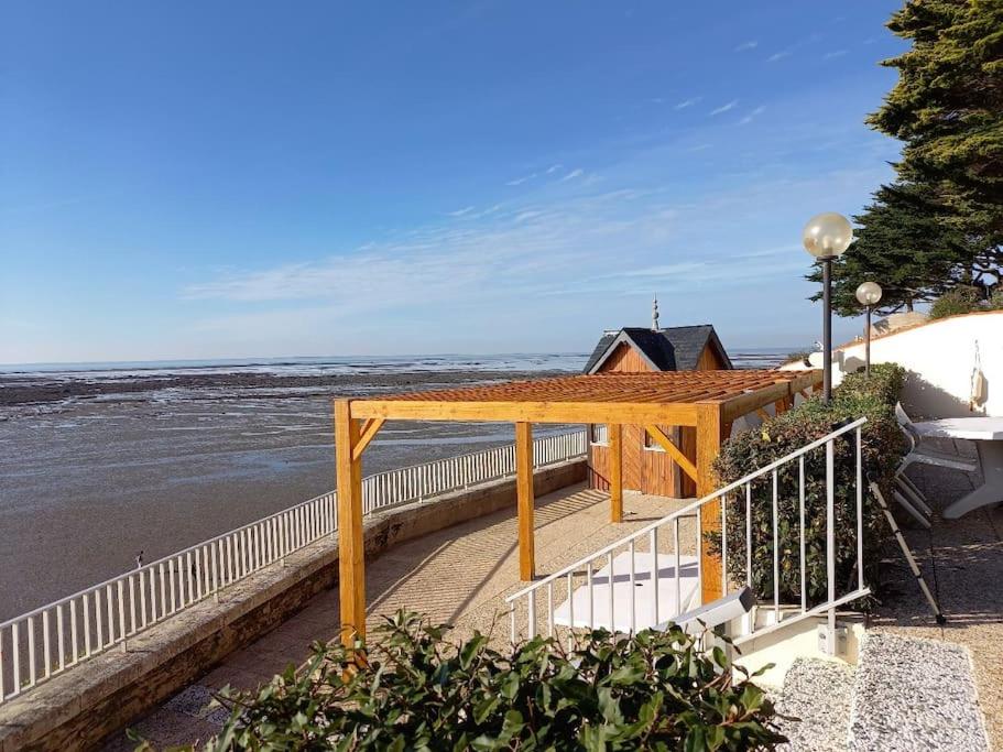 Una pasarela cubierta junto a la playa con el agua en Appart magnifique avec une vue exceptionnelle OLERON, en La Bernerie-en-Retz