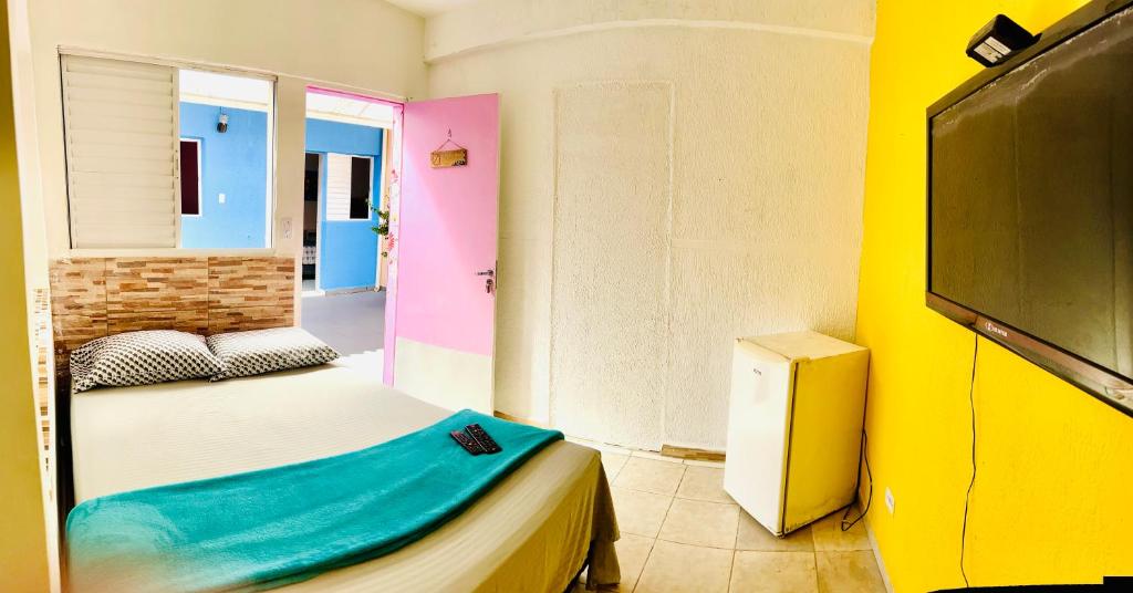 een kleine kamer met een bed en een televisie bij Pousada Villa Brasil Ocian in Praia Grande