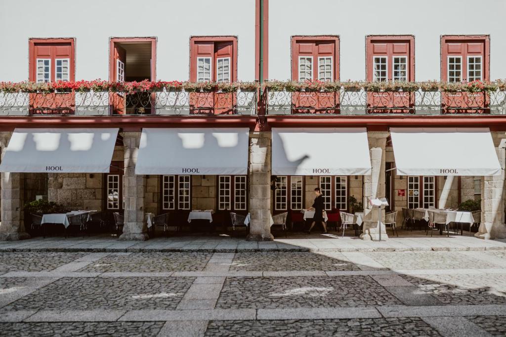 un ancien bâtiment avec des tables, des chaises et des fenêtres dans l'établissement Hotel da Oliveira, à Guimarães